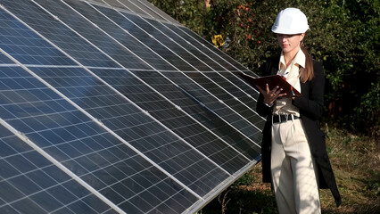 Wall Mural - Close-up of a young female engineer checking the operation of the sun and the cleanliness of photovoltaic solar panels. Concept renewable energy, technology, electricity, services, green