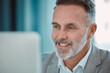 © peopleimages.com - Office, smile and mature man at computer with confidence, research and professional at consultancy. Advisor, project manager or happy businessman at desk for online support in business development