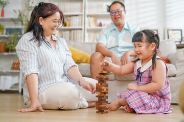 happy asian family playing wooden blocks tower game with a little female kid at home in the living room,family lifestyle,holiday,relaxation