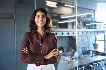 portrait of beautiful successful hispanic young business woman with crossed arms smiling at camera. 