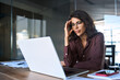 © Stock 4 You - Focused young businesswoman looking at laptop pc computer screen having headache, migraine. Latin business woman holding hand near temples, feeling stressed and tired sitting at workplace in office