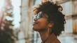 © progressman - a woman with sunglasses looking up at something in the sky with a building in the background