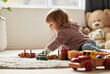 © CineLens2024/peopleimages.com - Young kid, toys and play in bedroom for development or learning, child in home for motor skills. Baby, house and relax game with wood cars for education or creativity, wellness or cognitive growth