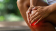 © RISHAD - Hands gently holding a painful knee, with a red highlight indicating discomfort, emphasizing the need for care and attention.