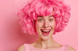 © Pacharee - Happy woman with funny face wearing wig on color background.