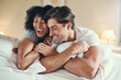 © aLListar/peopleimages.com - Laughing, man and woman on bed in morning for love, support and relax in apartment. Happiness, couple and together in home for date, care and comedy or joke with respect and care for weekend