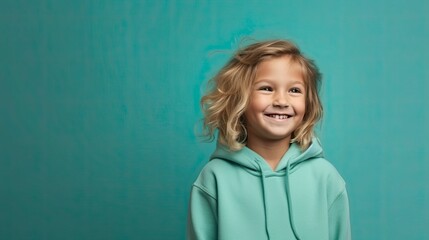 Wall Mural - cheerful young young child in clothes, simple teal background