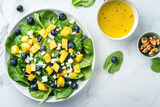 fresh lettuce salad with mango and blueberries, topped with feta cheese and a side of dressing