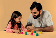 © john - Father and daughter playing leisure game against beige background