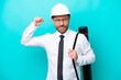 © luismolinero - Middle age architect man with helmet and holding blueprints isolated on blue background doing strong gesture
