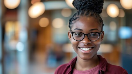 Wall Mural - A young Black woman smiles at the camera, wearing glasses and a burgundy shirt