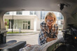 © Miljan Živković - mature blonde woman travel take stuff belongings from the back of car