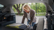 © Miljan Živković - mature blonde woman travel take stuff belongings from the back of car