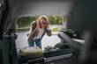 © Miljan Živković - mature blonde woman travel take stuff belongings from the back of car