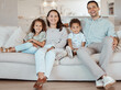 © SneakyPeakPoints/peopleimages.com - Parents, happy family and portrait of children in home together for care, love and bonding. Smile, mother and father with kids on sofa in living room for support, laughing and relax with siblings