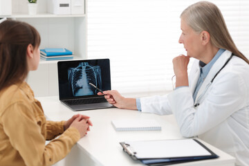 Sticker - Lung cancer. Doctor showing chest x-ray on laptop to her patient in clinic