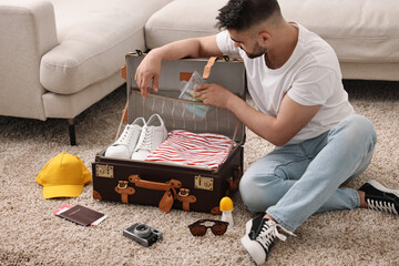 Sticker - Man packing suitcase on floor at home