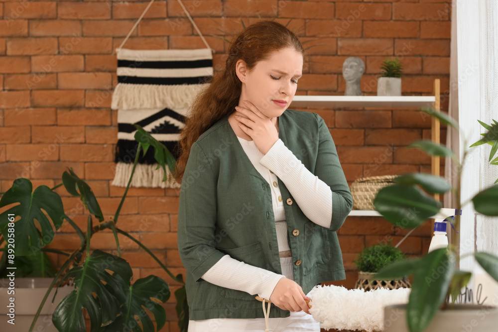 Sick young woman with sore throat and pp-duster at home