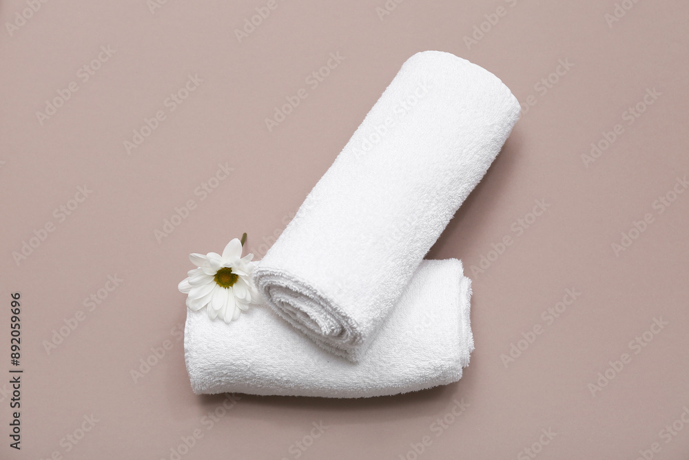 Composition with white soft towels and daisy flower on brown background