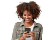 © CozyNessAI - A portrait of a young African American black woman with curly hair looking at her mobile phone and smiling, isolated in a transparent background. Cut out or PNG.