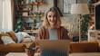 © Mahemud - Smiling freelancer using laptop at desk in living room, panoramic shot