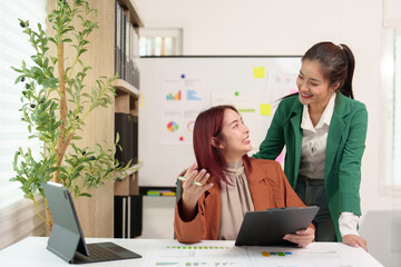 Wall Mural - Analysis. Discussion. Asian female economist and marketer pointing at financial data sheet to plan company's financial growth. Negotiation. Expressing ideas. Successful teamwork concept.