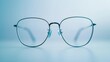 © Chano_1_na - Close-up of a pair of eyeglasses with sleek, thin frames on a smooth white surface, emphasizing simplicity and elegance