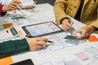 © M+Isolation+Photo - A group of people collaborates around a desk, discussing and reviewing user interface (UI) and user experience (UX) elements. usability, accessibility, and design principles for product development.