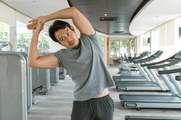 Wall Mural - Fitness asian Thai man stretching after done exercise, building muscles workout at gym, routine in the morning.