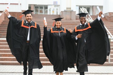 Wall Mural - education, graduation and people concept - group of happy international students in mortar boards and bachelor gowns with diplomas