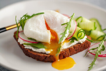 Wall Mural - Open sandwich with vegetables and poached egg in a plate on the table