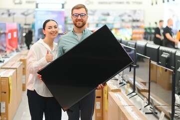 Wall Mural - Young couple chooses plasma TV in store of household appliances, electronics and gadgets. Buying new TV, sale day