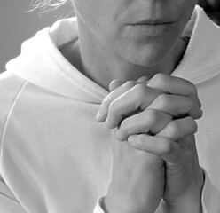 Wall Mural - woman praying to god with hands together on grey background with people stock photos stock photo	