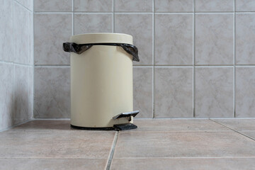 pedal lid trash can in the corner of a bathroom