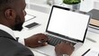 © munawaroh - A man working on a laptop at a desk with a plant and office supplies nearby.