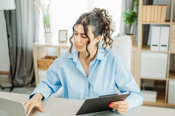 Wall Mural - One young beautiful caucasian business woman working in office on laptop and looking through charts