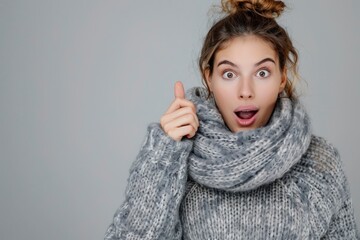 Excited young woman in gray sweater scarf pointing index finger aside keeping mouth open isolated on grey background. Healthy fashion lifestyle people emotions cold season concept - generaetive ai