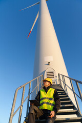 Canvas Print - Engineer with digital tablet controls wind turbines