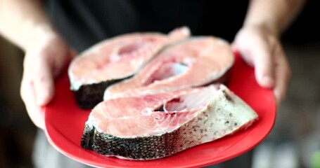 Wall Mural - Cook holding in his hands plate with raw red fish closeup 4k movie slow motion. Healthy eating concept