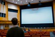 © tiena - People in modern conference hall with a blank big screen for presentation. AI generative
