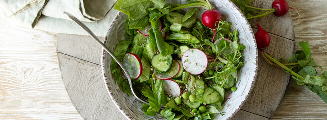 Wall Mural - plate with spring salad with radishes, cucumbers and green peas on the table