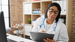 © Krakenimages.com - Hispanic woman doctor reviewing medical records on a clipboard in a modern clinic office.