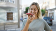 © Krakenimages.com - Smiling young blonde woman using smartphone on city street