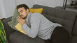 © Krakenimages.com - Hispanic man napping on a couch indoors, with cozy pillows, portraying everyday relaxation in a home setting.