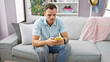 © Krakenimages.com - A young hispanic man with a beard focused on texting on his smartphone in a stylish living room setting.