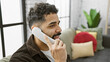 © Krakenimages.com - Handsome man talking on a landline phone in a cozy apartment living room with colorful cushions.