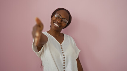 Wall Mural - Smiling african woman extending hand over pink background in a warm gesture