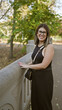 © Krakenimages.com - Smiling young woman with glasses dressed in black enjoying a sunny day in a leafy park.