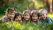 © At My Hat - A group of children are laying on the grass and smiling. The children are of different ages and genders