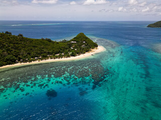 Wall Mural - aerial view on clear sunny day of tropical island beach with shallow turquoise water and corals reef